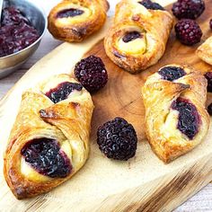 croissants with blueberries and butter on a cutting board next to other pastries