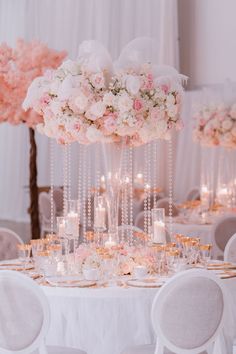 a table with white and pink flowers, candles and chandeliers in the center