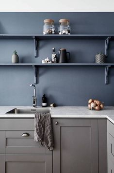 a kitchen with blue walls and shelving above the sink