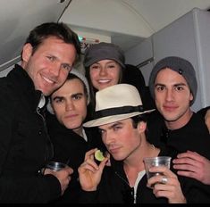 a group of young men standing next to each other with drinks in their hands and smiling at the camera