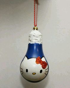 a hello kitty ornament hanging from a hook on a white wall with a red string