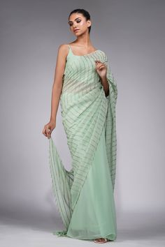 Sage green pre-draped saree crafted in georgette base with badla embroidery in stripe pattern. Paired with a  padded sleeveless blouse. Comes along with cape hand embroidered with gold and white pearls and separate petticoat.
Components: 4
Pattern: Embroidery
Type Of Work: Badla, Pearls, Cutdana
Neckline: Square Neck
Sleeve Type: Sleeveless
Fabric:  Saree: Georgette, Blouse : Silk, Cape: Star Net, Petticoat: Satin
Color: Green
Other Details: 
Blouse:
Padded
Cape:
Cutdana hangings
Occasion: Sange Elegant Pre-draped Pista Green Saree With Sheer Dupatta, Green Georgette Pre-draped Saree With Traditional Drape, Green Georgette Pre-draped Saree, Designer Wear Pista Green Georgette Pre-draped Saree, Evening Green Blouse Piece With Sheer Dupatta, Green Pre-draped Saree With Sheer Dupatta For Evening, Evening Green Georgette Saree, Elegant Pista Green Pre-draped Saree With Sheer Dupatta, Elegant Floor-length Pre-draped Saree In Pista Green