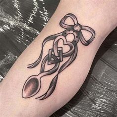 a tattoo on the leg of a person with scissors and heart shaped ribbon around it