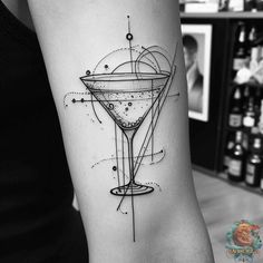 a woman's arm with a tattoo on it and a martini in the middle