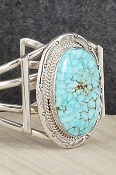 This Kingman turquoise and sterling silver bracelet was made by Navajo silversmith Raymond Delgarito. The inside is signed RD and stamped sterling.Size: 5 1/2" (will fit up to a 6 1/2" wrist)Gap: 1"Width: 1 3/4"Free shipping on all orders! We ship with USPS and always include tracking. All orders ship within a day of payment.Returns are accepted up to 30 days after you receive your order. Just send us a message. Our shop offers cash back or store credit. The item must be returned in new conditio Southwestern Blue Oval Bracelets, Artisan Sterling Silver Turquoise Bracelet Collectible, Western Style Blue Sterling Silver Bracelet Gift, Sterling Silver Turquoise Bracelet Gift, Southwestern Style Stamped Blue Bracelets, Gift Turquoise Sterling Silver Bracelet, Southwestern Sterling Silver Cuff Bracelet In Blue, Handmade Turquoise Sterling Silver Southwestern Bracelet, Collectible Bohemian Blue Sterling Silver Bracelet