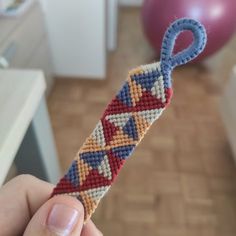 a hand holding a piece of beaded fabric with scissors in it's end