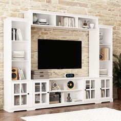 a white entertainment center with bookshelves and a flat screen tv mounted on the wall