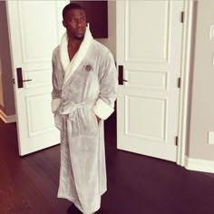 a man in a bathrobe standing on a hardwood floor next to two doors