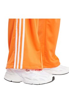 A Trefoil logo and 3-Stripes down the legs bring classic adidas style to these soft and comfortable recycled-polyester tricot track pants. Elastic waist Side zip pockets 100% recycled polyester Machine wash, tumble dry Imported Adidas Relaxed Fit Moisture-wicking Bottoms, Orange Athleisure Jogging Bottoms, Orange Athleisure Bottoms For Jogging, Adidas Sports Nylon Pants, Adidas Nylon Sports Pants, Casual Adidas Nylon Pants, Casual Nylon Adidas Pants, Adidas Sporty Wide Leg Pants, Adidas Sporty Wide-leg Pants