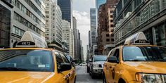 taxi cabs are lined up on the street in front of tall buildings and skyscrapers