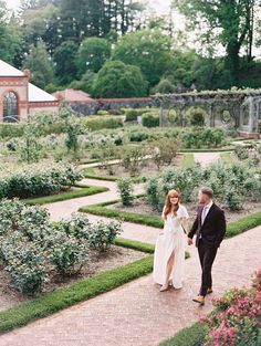 a bride and groom walking through the garden