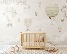 a baby's room with hot air balloons in the sky and a crib