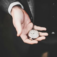 a person in a suit holding an old pocket watch