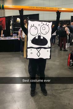 a man is holding up a sign that says best costume ever in front of him