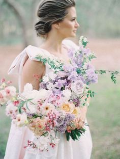 a woman holding a bouquet of flowers in her hand and looking off into the distance