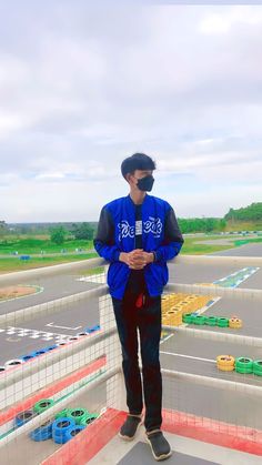 a man standing on top of a parking lot wearing a blue jacket and black pants