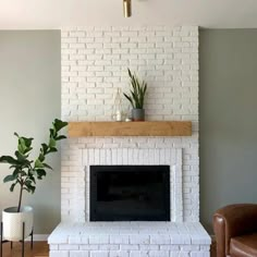 a living room with a white brick fireplace and potted plants on the mantel