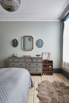 a bedroom with a bed, dresser and two mirrors on the wall next to each other