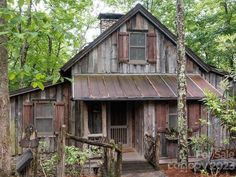 an old wooden house in the woods surrounded by trees