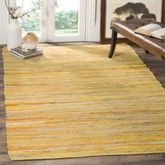 a yellow area rug in a living room with a wooden bench and large open window