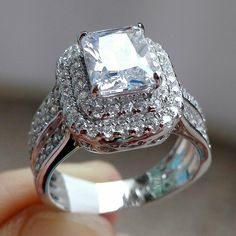 a close up of a diamond ring on a person's finger with the center stone surrounded by smaller diamonds