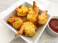 some shrimp sticks are in a white square bowl with dipping sauce on the side,