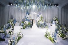 a bride and groom standing in front of a wedding ceremony arch decorated with blue and white flowers