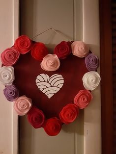 a heart shaped wreath made out of rolled paper flowers hangs on the front door frame