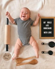 a baby laying on top of a bed next to utensils and a sign