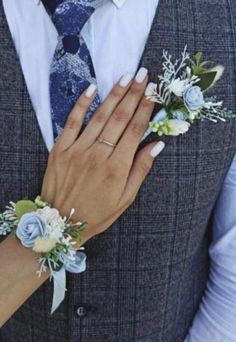 a man in a suit and tie with flowers on his wrist