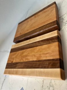 three wooden cutting boards sitting on top of a white marble countertop next to each other