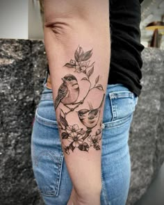 a woman's arm with a bird and flowers tattoo on it