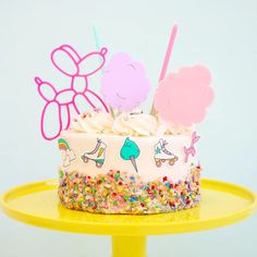 a birthday cake with sprinkles and decorations on it sitting on a yellow plate