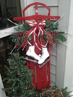 a red sled with christmas decorations and ice skates hanging from it's side