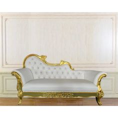 a white and gold couch sitting on top of a hard wood floor next to a wall