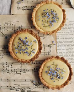 three pies with blue flowers on top of sheet music paper and an old book