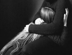 black and white photograph of two women hugging each other in front of a dark background