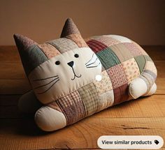 a patchwork cat pillow sitting on top of a wooden table