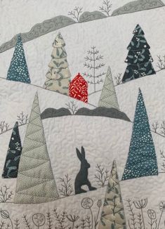 a quilted wall hanging with trees and a rabbit