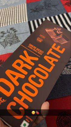 a person holding up a book with the title dark chocolate written in orange on it