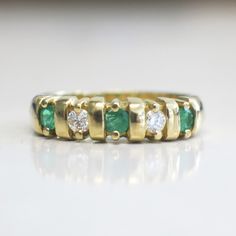 This stunning 18K yellow gold ring features two very white round brilliant cut diamonds and three bright green round emeralds. This ring is perfect for an anniversary band, wedding band, or stackable ring. The contrast of the colors makes sure this ring stands out! Metal: 18K Yellow Gold Diamonds: .20 CTW, VS1-VS2, E-F Color Emeralds: 3 MM Each Band Width: 3.44 - 5.00 MM Size: 7 For a greater selection of jewelry please visit our website at www.BlackMarketLLC.com If you have any questions about Classic Green Emerald Ring With Single Cut Diamonds, Classic Green Rings With Single Cut Diamonds, Classic Green Diamond Ring With Single Cut Diamonds, Green Round Diamond Ring With Channel Set, Green Diamond Ring With Single Cut Diamonds For Anniversary, Green Emerald Ring With Single Cut Diamonds For Promise, Emerald Green Promise Ring With Single Cut Diamonds, Classic Green Channel Set Emerald Ring, Green Emerald Ring With Single Cut Diamonds