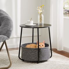 an orange cat sitting in a grey basket on top of a table next to a gray chair