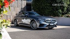 the mercedes s - class coupe is parked in front of a building with red flowers