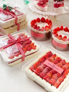 there are many desserts on the table and one is covered in strawberries with a red ribbon