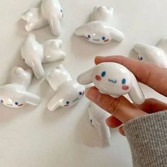 a hand is holding a small white toy with blue eyes and nose shapes on it