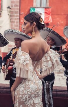 a woman in a white dress and sombreros is walking down the street with her back to the camera