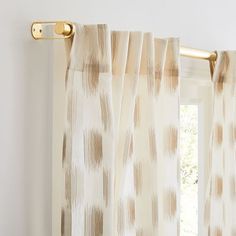 an open window with white curtains and gold hardware on the curtain rod in front of it