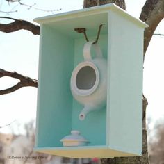 a blue birdhouse with a white toilet paper dispenser hanging from it's side