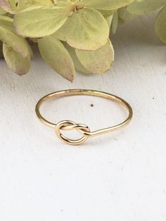 a gold ring sitting on top of a white table next to flowers and leaves,