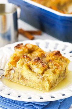 a piece of bread pudding on a plate with a fork and cup in the background